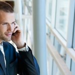 A man talking on the phone looking out of an office window.