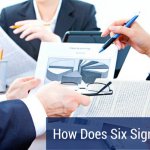 Close up of the hands of three business professionals reviewing a six sigma contract.