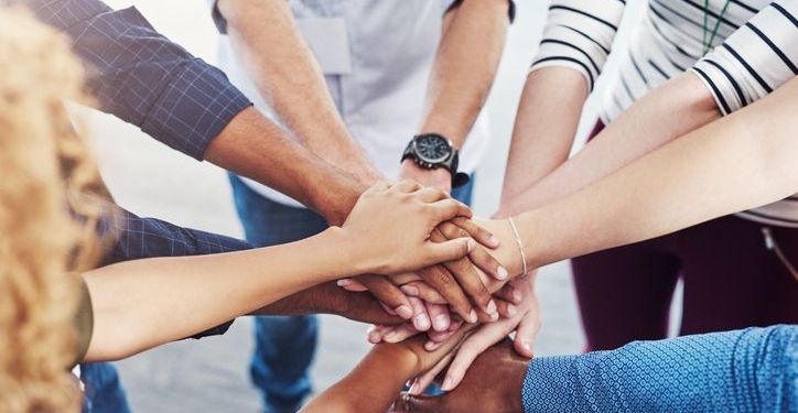 Closeup shot of a group of people joining hands in a huddle