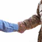 Military person and civilian shaking hands standing on white background
