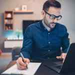 Businessman using laptop and doing paperwork at home