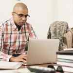 Mixed race soldier using laptop at home