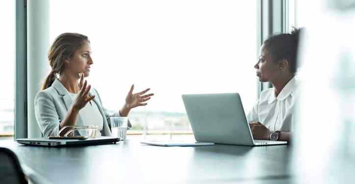 Concept of a Compensation and Benefits Manager sitting with an employee in an office setting